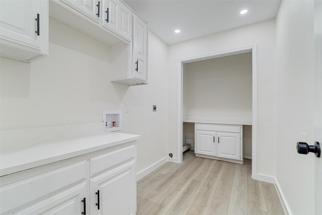 clothes washing area with electric dryer hookup, hookup for a washing machine, cabinets, and light wood-type flooring