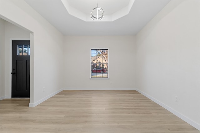 unfurnished room featuring light wood-type flooring and a raised ceiling