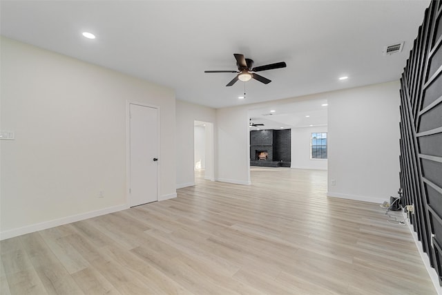 unfurnished living room with ceiling fan, light hardwood / wood-style flooring, and a brick fireplace