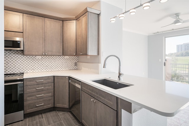 kitchen featuring decorative light fixtures, backsplash, kitchen peninsula, sink, and stainless steel appliances