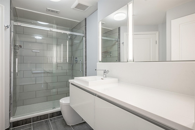 bathroom featuring toilet, a shower with shower door, and vanity