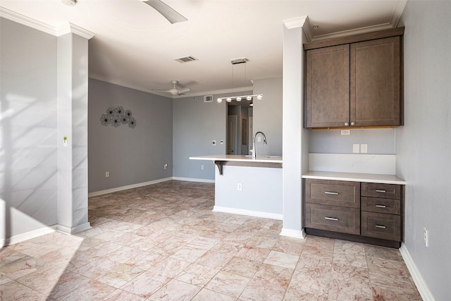 kitchen featuring sink, crown molding, dark brown cabinets, and decorative light fixtures