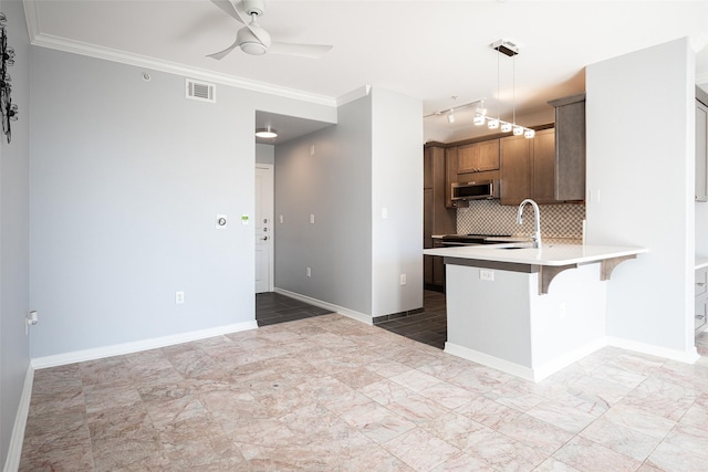 kitchen featuring ceiling fan, backsplash, kitchen peninsula, hanging light fixtures, and a breakfast bar area