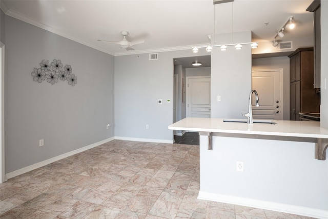 kitchen with ceiling fan, sink, a breakfast bar area, and pendant lighting