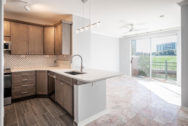 kitchen with pendant lighting, stainless steel appliances, decorative backsplash, sink, and kitchen peninsula