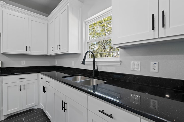 kitchen with white cabinetry, sink, and dark stone counters