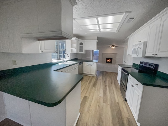 kitchen with kitchen peninsula, sink, appliances with stainless steel finishes, light hardwood / wood-style floors, and white cabinetry