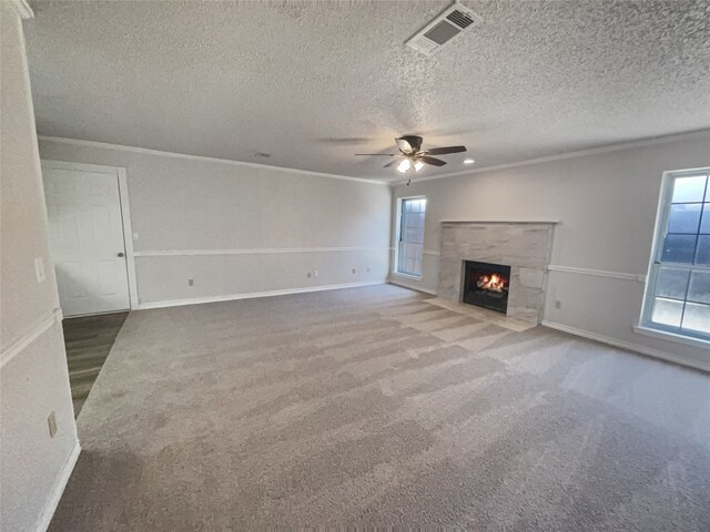 unfurnished living room featuring a textured ceiling, a fireplace, ceiling fan, and dark carpet