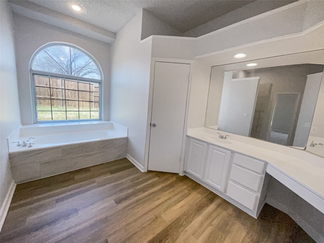 bathroom with a textured ceiling, vanity, a bathing tub, and hardwood / wood-style flooring