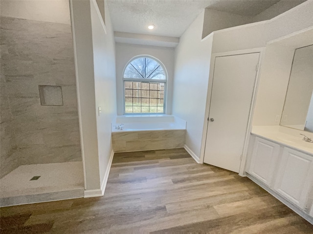 bathroom with hardwood / wood-style flooring, a washtub, a textured ceiling, and vanity