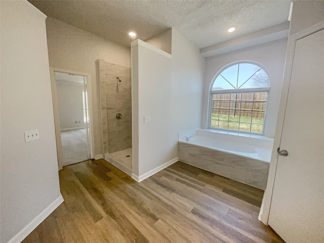 bathroom with hardwood / wood-style floors, a textured ceiling, and separate shower and tub