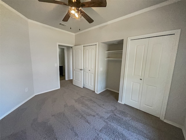 unfurnished bedroom featuring ceiling fan, dark carpet, multiple closets, and ornamental molding