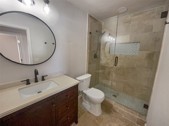 bathroom with toilet, tile flooring, a shower with shower door, and vanity