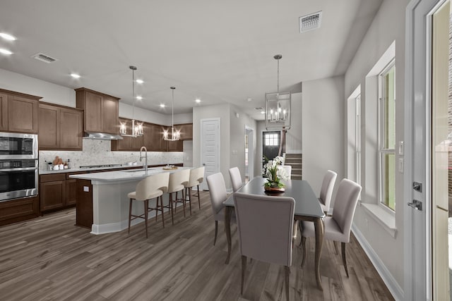 dining room with dark hardwood / wood-style flooring, a notable chandelier, and sink