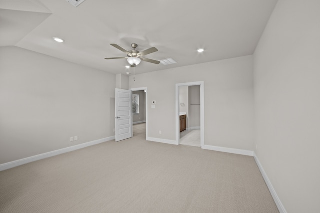 unfurnished bedroom featuring ceiling fan, vaulted ceiling, light colored carpet, and ensuite bath