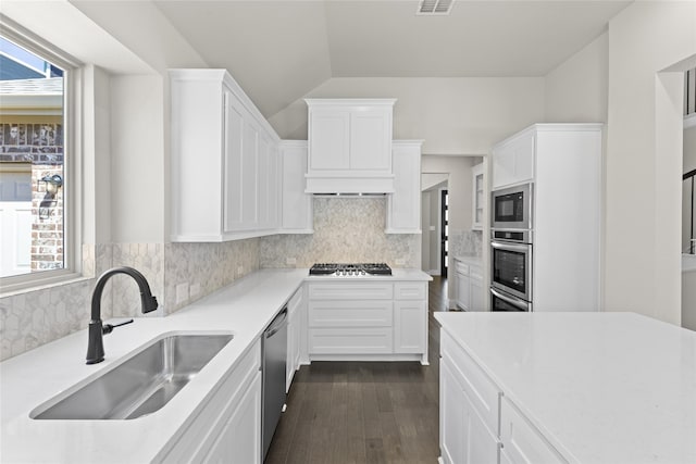 kitchen featuring sink, dark wood-type flooring, white cabinetry, stainless steel appliances, and tasteful backsplash