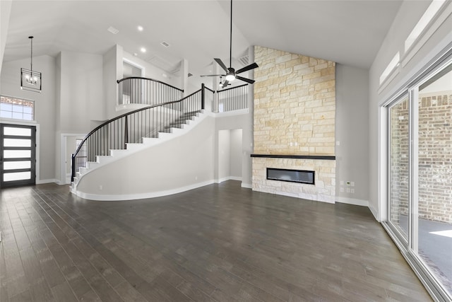 unfurnished living room with high vaulted ceiling, ceiling fan with notable chandelier, a fireplace, and dark hardwood / wood-style flooring