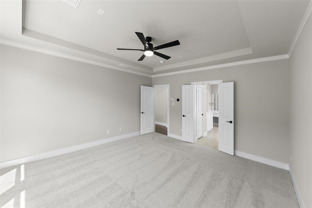 unfurnished bedroom with crown molding, light carpet, ceiling fan, and a tray ceiling