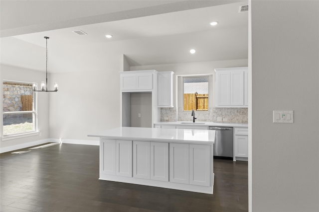 kitchen featuring white cabinetry, stainless steel dishwasher, a center island, and decorative backsplash