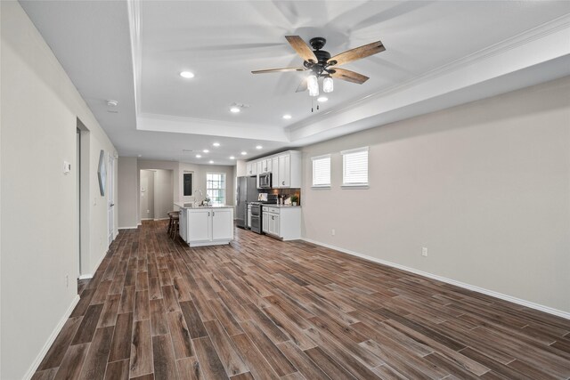 interior space with dark hardwood / wood-style floors, ornamental molding, a raised ceiling, and ceiling fan