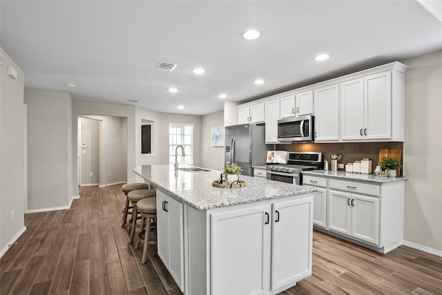 kitchen with stainless steel appliances, sink, a center island with sink, and white cabinets