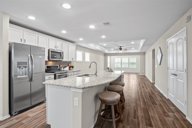 kitchen featuring dark wood-type flooring, sink, an island with sink, white cabinetry, and stainless steel appliances