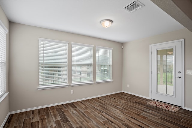 spare room with dark wood-type flooring and a healthy amount of sunlight