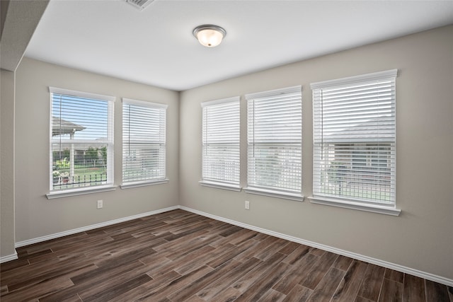 empty room featuring dark hardwood / wood-style flooring and a wealth of natural light