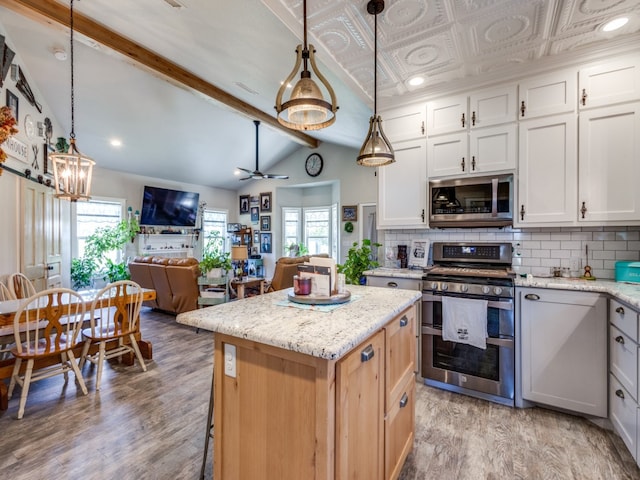 kitchen featuring appliances with stainless steel finishes, decorative light fixtures, white cabinets, and a healthy amount of sunlight