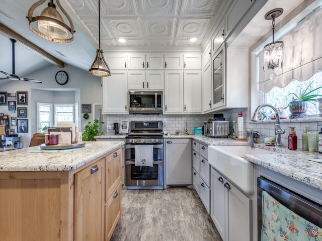 kitchen featuring light stone countertops, decorative light fixtures, stainless steel appliances, white cabinetry, and light wood-type flooring