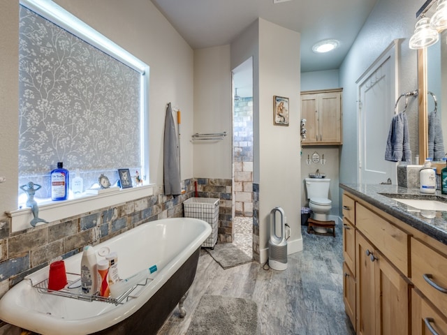 bathroom with tile walls, hardwood / wood-style floors, toilet, a bathtub, and vanity