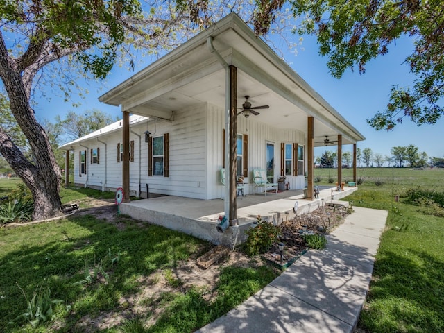 view of front facade with a front yard, ceiling fan, and covered porch