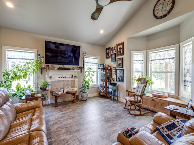 living room with light hardwood / wood-style floors, ceiling fan, a tile fireplace, and lofted ceiling