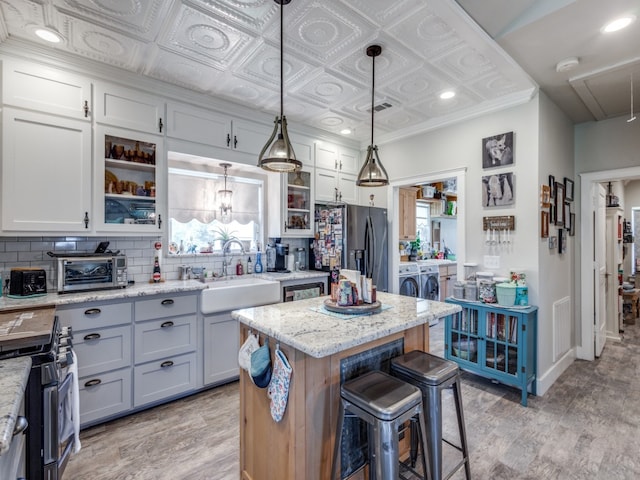 kitchen featuring a kitchen island, appliances with stainless steel finishes, decorative light fixtures, and light stone countertops