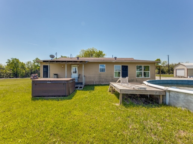 rear view of property with a hot tub, an outdoor structure, and a lawn