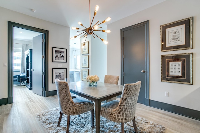 dining room featuring baseboards, a chandelier, and light wood-type flooring