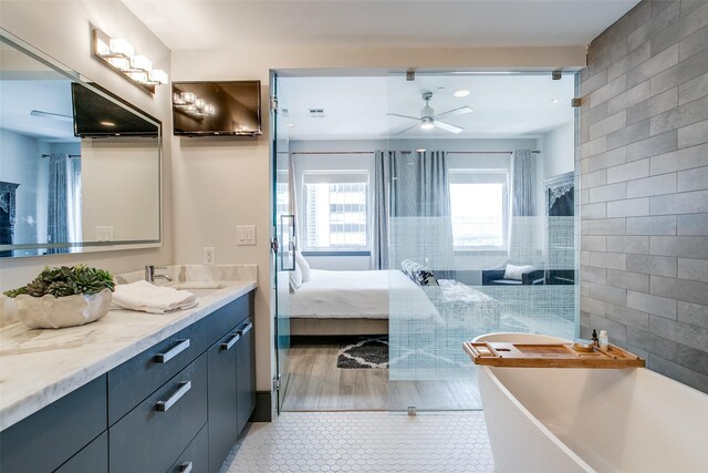full bath with tile walls, tile patterned floors, vanity, a ceiling fan, and a freestanding bath