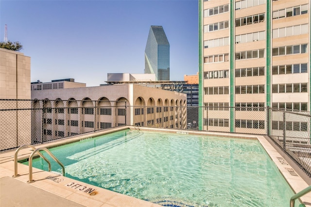 view of pool featuring a city view and fence