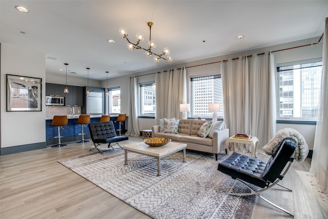 living room with baseboards, light wood-type flooring, and an inviting chandelier