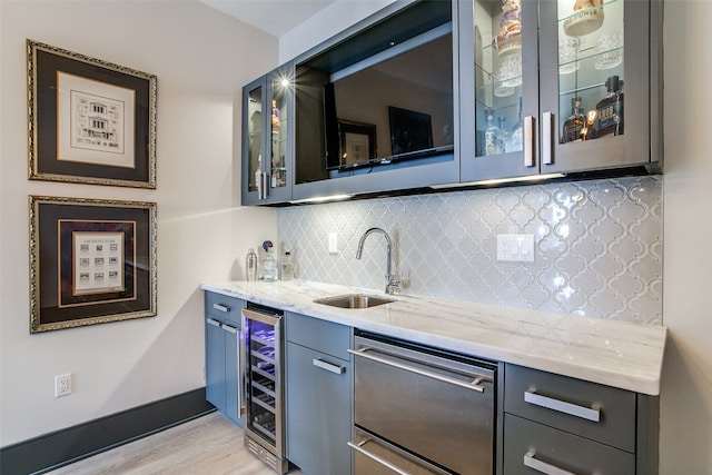 bar featuring backsplash, dishwasher, light stone counters, sink, and beverage cooler