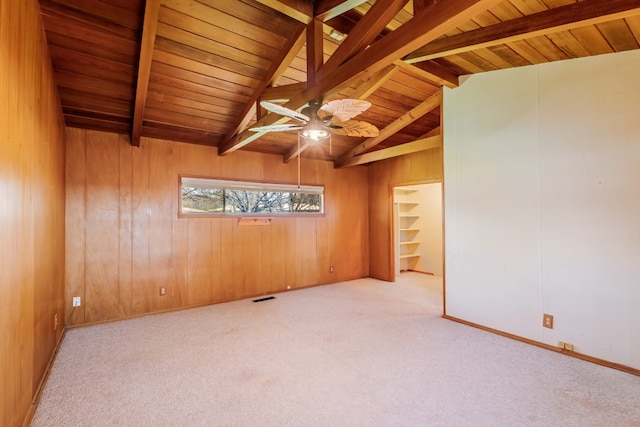 carpeted spare room featuring lofted ceiling with beams, wooden walls, wooden ceiling, and ceiling fan