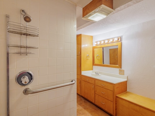 bathroom with a textured ceiling, tile flooring, oversized vanity, and tiled shower