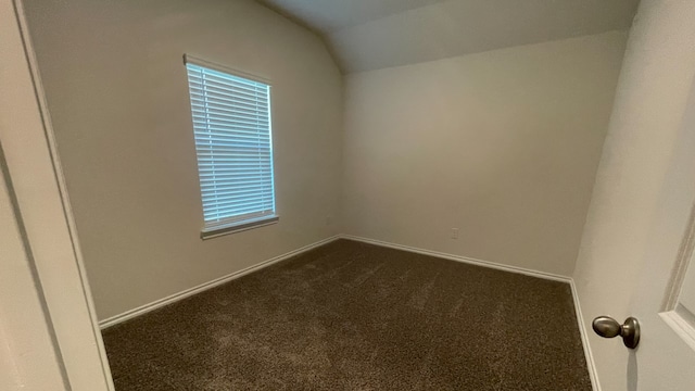 carpeted empty room featuring lofted ceiling