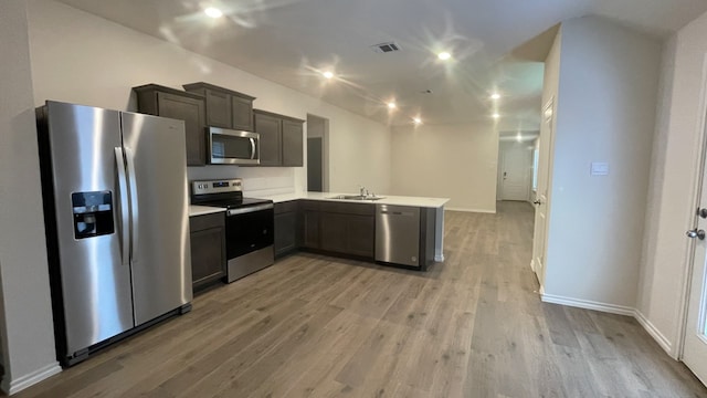 kitchen with sink, light wood-type flooring, kitchen peninsula, and stainless steel appliances