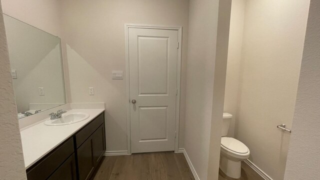 bathroom featuring toilet, hardwood / wood-style floors, and vanity