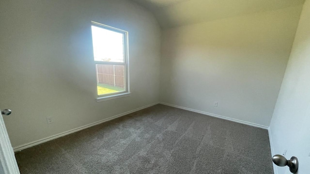 carpeted spare room featuring lofted ceiling