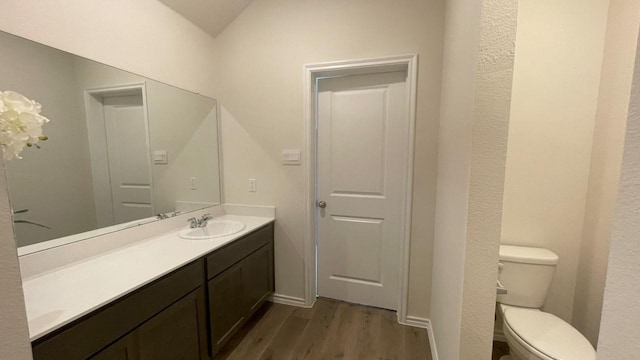 bathroom featuring toilet, vaulted ceiling, hardwood / wood-style flooring, and vanity