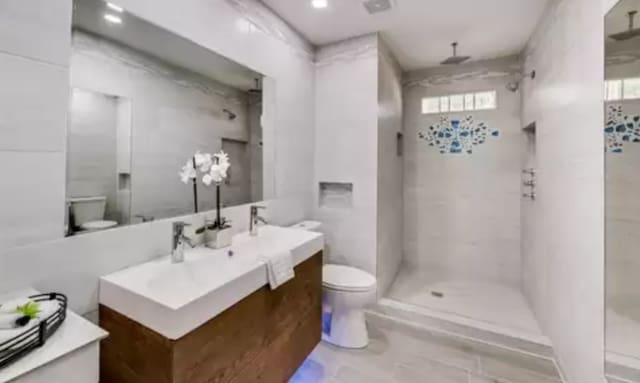 bathroom with vanity, tile floors, a tile shower, and toilet