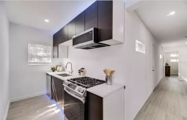 kitchen with stainless steel range with gas stovetop, light hardwood / wood-style floors, and sink