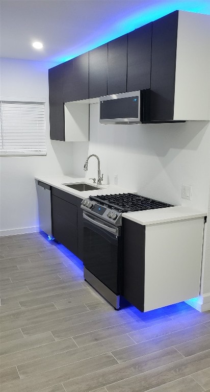 kitchen featuring stainless steel appliances, light wood-type flooring, and sink